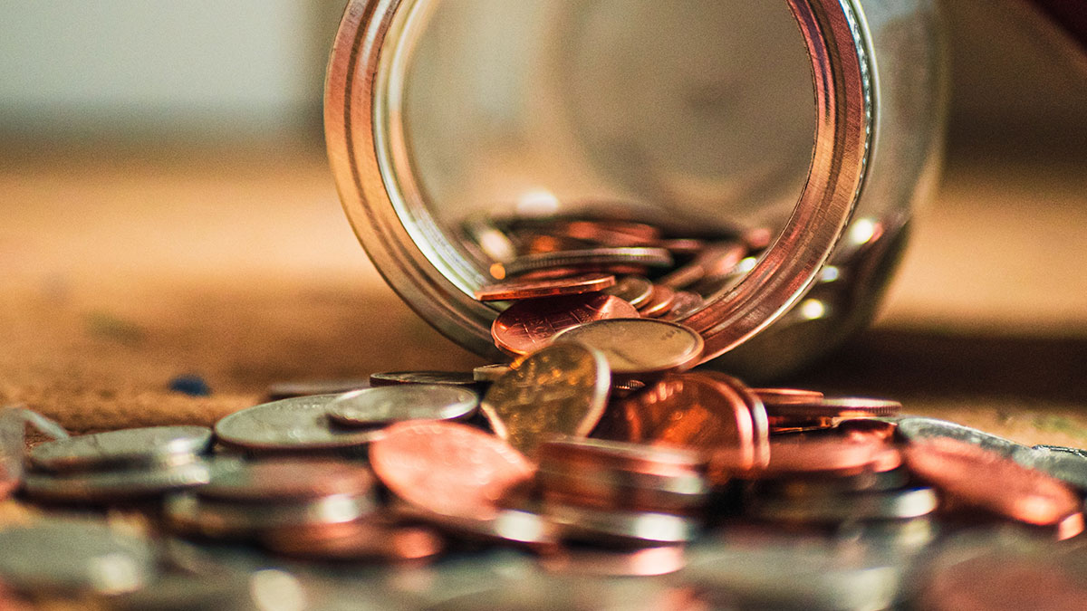 Coins spilling from a mason jar laying on its side