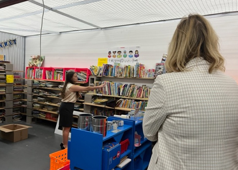 A woman organizes books on a bookshelf