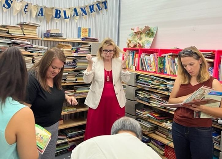 A group of people organize books, surrounded by bookshelves