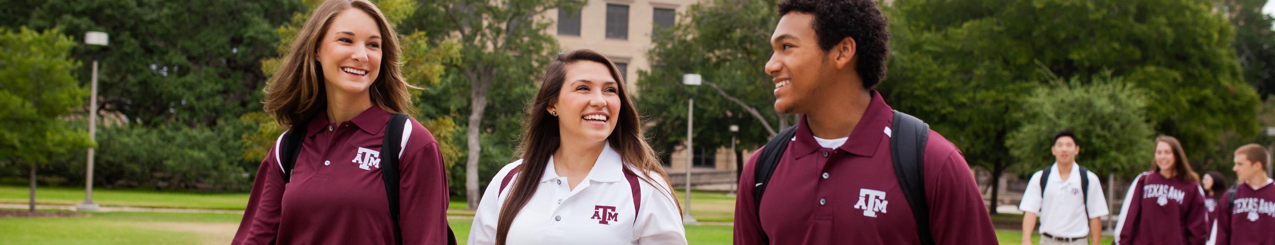 Three students dressed in maroon and white polos walking to class